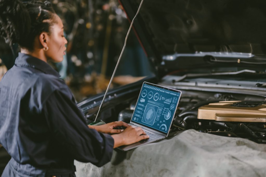 garage mechanic car engine engineer woman staff worker using laptop computer turning engine