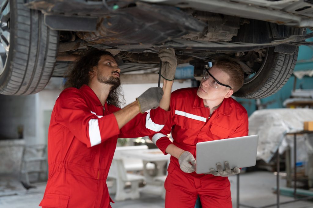 Two mechanic man repairing axle and suspension under car